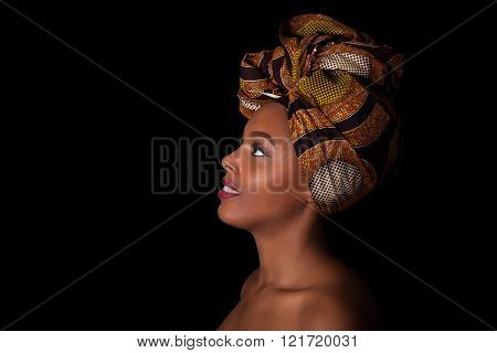 Young beautiful african woman wearing a traditional headscarf, Isolated over black background
