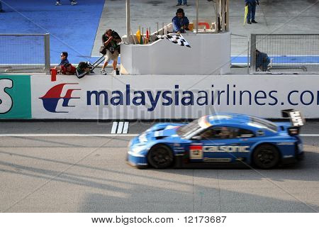 SEPANG, na Malásia - 21 de junho: Carro de The Calsonic pulso GTR Nissan (12) tendo a bandeira quadriculada ganhar