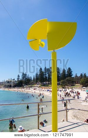 COTTESLOE,WA,AUSTRALIA-MARCH 12,2016: Rotating bright yellow sculpture with tourists at the 