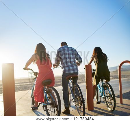 group of friends on bikes setting off towards the setting sun with backs to the camera