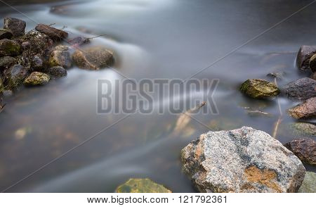 Close Up Of River With Stones And Plants