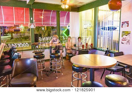 LAKE HAVASU USA - JULY 8 2008: family enjoys the typical pizza restaurant and Bar in Lake Havasu and watches TV while dining. The bar is illuminated with neon lights.