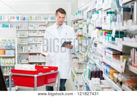 Male Pharmacist Updating Stock In Digital Tablet