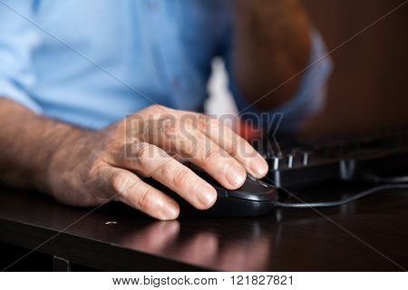 Man Using Computer Mouse At Desk In Class