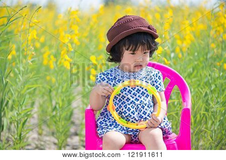 Cute Asian girl wearing white dress in yellow sunhemp flower field