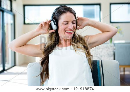 smiling woman sitting on a couch listening to music through her heaphones