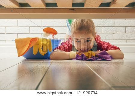 Charming little helper. Cute little child girl makes cleaning the house. Girl wipes the floor.