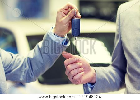 auto business, car sale, deal and people concept - close up of male hands with car key in auto show or salon
