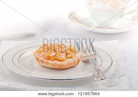 High key image of single bake apple tart with on white and silver plate.