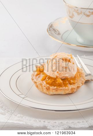 High key image of single bake apple tart with orange pineapple ice-cream.