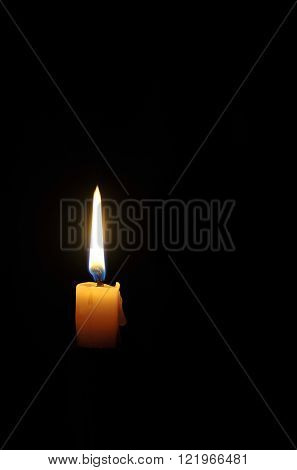 Single wax candle flame burning in darkness.