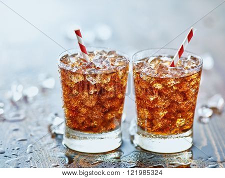 side by side glasses of ice cold cola soda pop with retro striped straws