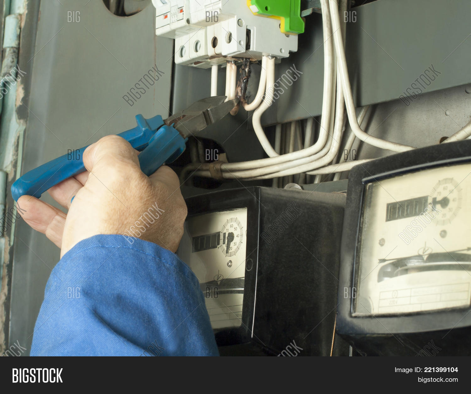 Worker man cutting electrical wires with pliers in fuse box. Electrical background.