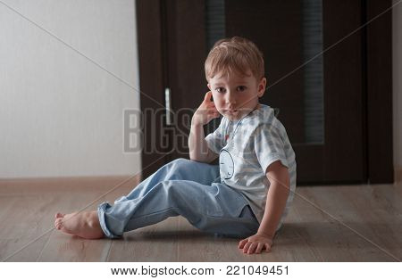 portrait of a child sitting at home on the floor barefoot