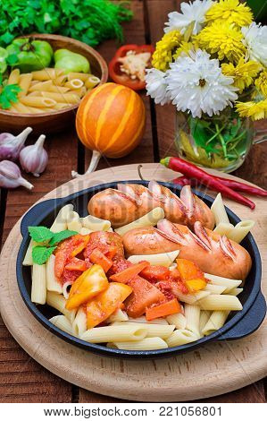 Pasta with sausages and lecho. Wooden rustic background. Top view. Selective focus