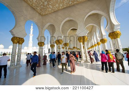 ABU DHABI, UNITED ARAB EMIRATES - DEC 28, 2017: Moslims and tourists are visiting the Sheikh Zayed Mosque in Abu Dhabi. It is the largest mosque in the country.