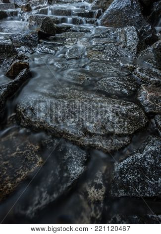 Waterfall Runs Through Trail Stepping Stones underneath
