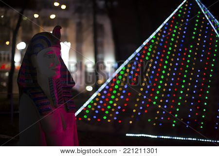Belarus, Gomel, January 7, 2018. Miniature Egyptian statue of the pharaoh and pyramid of Cheops in New Year's lights