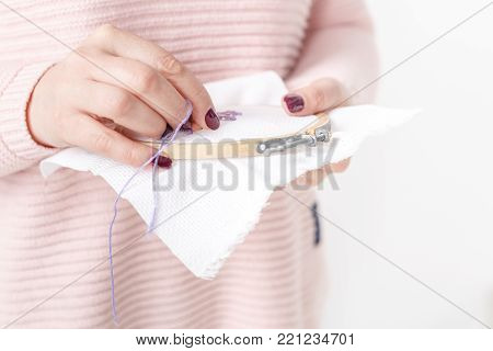 cross-stitched pillow in female hands close up
