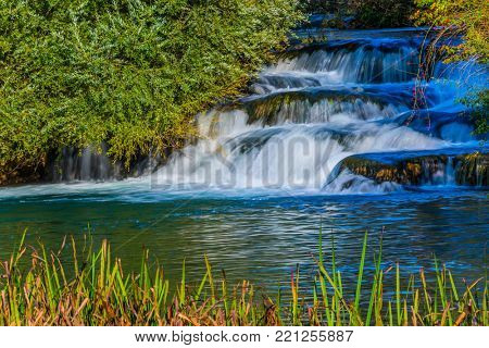 Slunj, Croatia. Little tourist town on the river Korana. Cascade waterfalls are lit by sunset. The concept of ecological, pedestrian and photo tourism