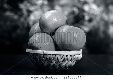 Close up of fresh ripe oranges,Citrus aurantium in a basket on wooden surface.