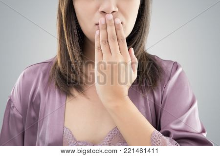 Asian woman in purple nightgown use both hands close mouth for Not commenting or refusing against gray background