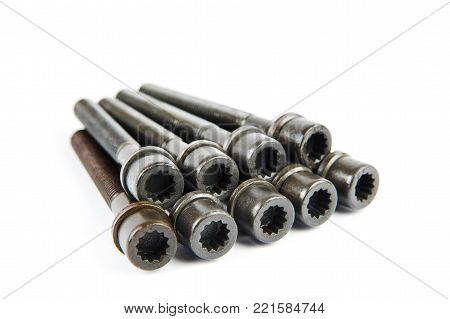 A set of new cylinder head bolts in oil on a white isolated background are shot in perspective at a wide angle. Spare parts for car repair