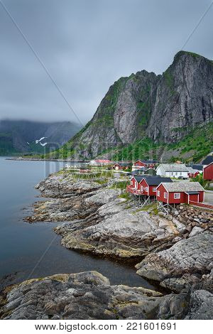 Traditional red rorbu cottages under the  Lilandstinden mountain peak in Hamnoy village, Lofoten islands, Norway. Long exposure.