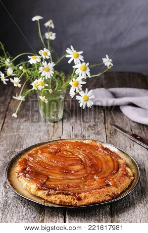 Traditional homemade banana caramel pie on vintage wooden table decorated a bouquet of chamomiles. Upside down banana cake. Selective focus