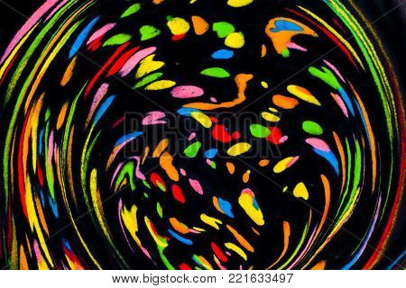 Colorful abstract acrylic painting on water. Natural dynamic mixture of oil colored pigments fluid spots on black background. Naturally blurred.
