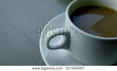 a brown coffee in the with cup on the wooden table