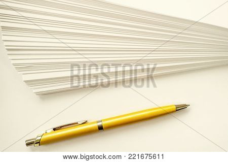 a stack of sheets of white paper and ball point gold pen writing set