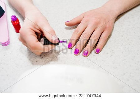 Hand paints the nails, gel purple, gel nail manicure.