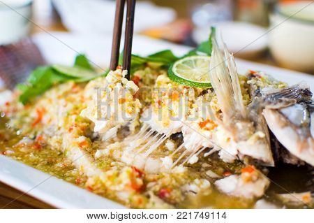 Steamed thai flavor sour and spicy fish served on the plate in restaurant