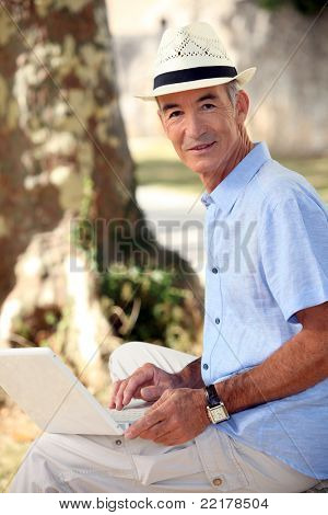 Mężczyzna w średnim wieku siedział w parku z laptopa