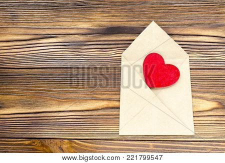 kraft paper envelope with wooden red heart on wooden table with copy space
