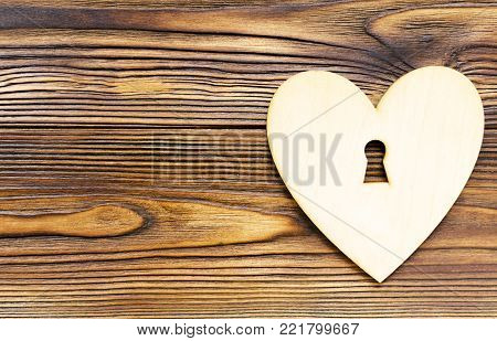 wooden heart with keyhole on wooden background with copy space