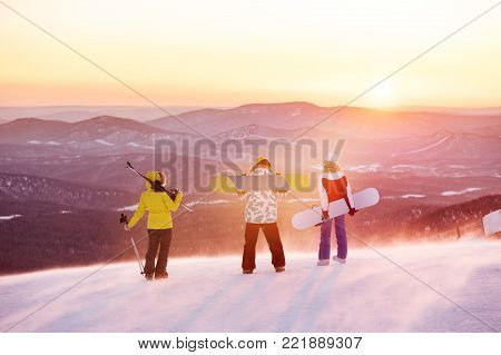 Group of three friends at ski resort against sunset