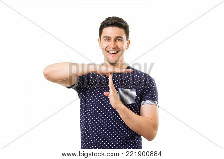 Young cheerful handsome man showing timeout gesture by hands isolated on white background
