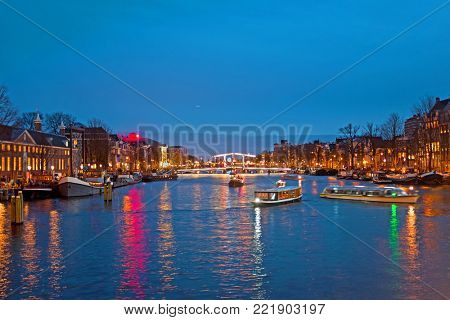 Cruising on the river Amstel in Amsterdam at the Tiny Bridge at sunset in the Netherlands