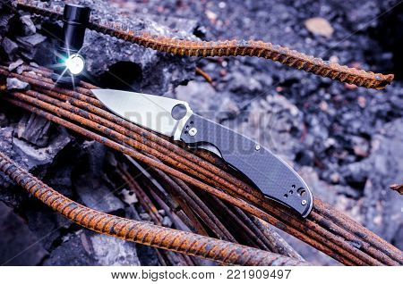 Tactical knife and flashlight. A bright flare from the lantern. Diagonal lines.