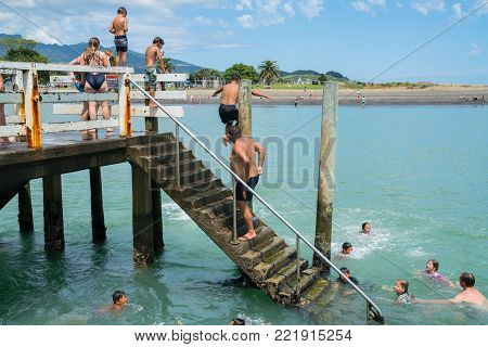 RAGLAN NEW ZEALAND - JANUARY 14, 2018; Summer fun in Raglan mostly local Maori boys jumping from the small wharf in small New Zealand town on North Island's West Coast.