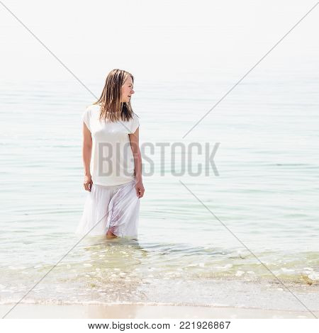 Beautiful blonde woman standing at the sea