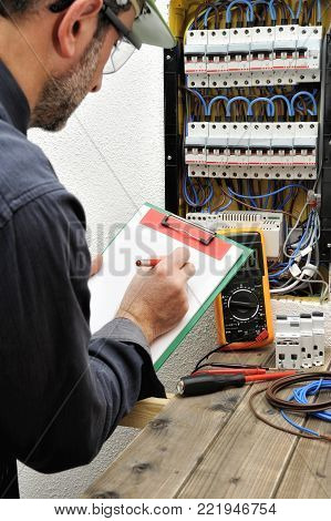 Electrical Technician writes in a notebook the data collected on a residential electric panel