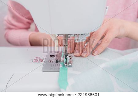womans hadns workin on sewing machine close up