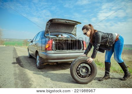 woman get wheel from the trunk to repair it
