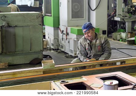 Lipetsk, Russia - June 15, 2017: The worker polishes the primer layer. Work on the preparation of the machine bed for subsequent painting.