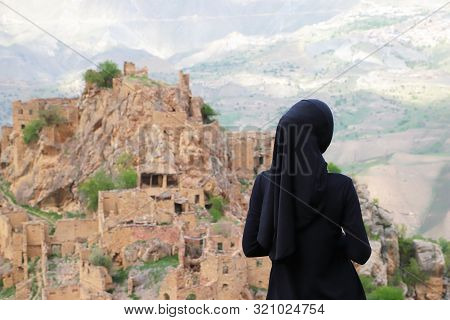 Muslim Woman In Hijab Standing On The Mountain And Looking To The Gamsutl. Republic Of Dagestan, Rus