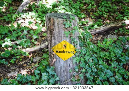 Yellow Hiking Trail Mark On A Wooden Stump In Nature. Sign Translation: Wanderweg - Trail, Hiking Pa