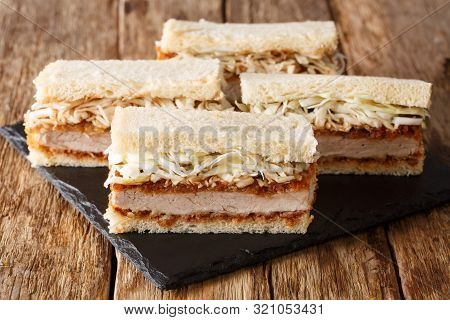 Homemade Sandwiches With Pork Cutlet, Sauce And Fresh Cabbage Close-up On A Slate Board. Horizontal